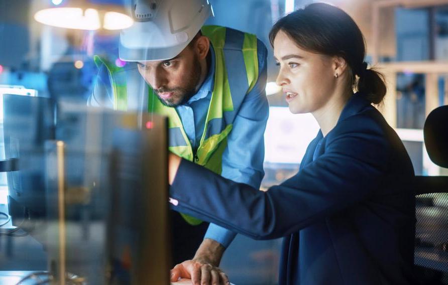 Woman and man in PPE look onto a computer